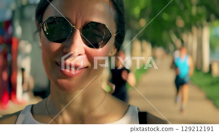 Portrait of a beautiful woman wearing sunglasses on a warm summer afternoon, close-up 129212191