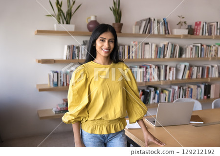 Young woman standing in modern creative workspace look at camera 129212192