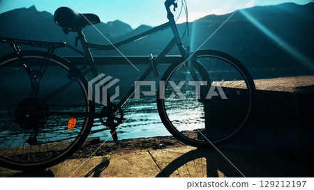 Parked bicycle on the lake Bourget shore on a sunny day. Aix-les-Bains, France Parked bicycle on the lake Bourget shore on a sunny day. Aix-les-Bains, France 129212197