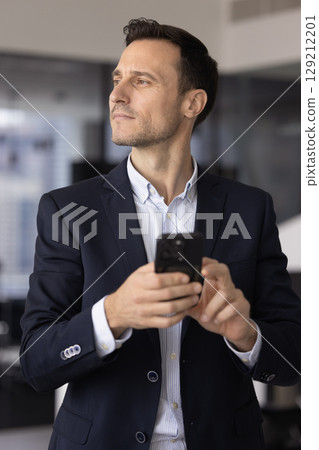 Pensive middle-aged businessman holding modern smart phone Pensive middle-aged businessman holding modern smart phone 129212201