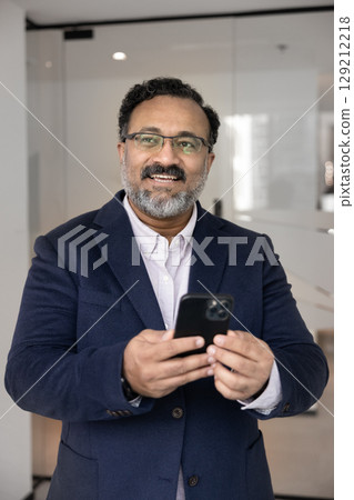 Mature businessman holding phone look aside with dreamy smile Mature businessman holding phone look aside with dreamy smile 129212218