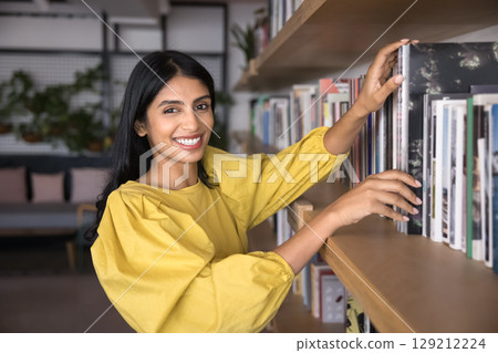 Indian woman standing by bookshelf with lot of diverse literature Indian woman standing by bookshelf with lot of diverse literature 129212224