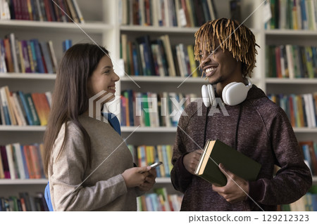 Teen girl holding phone enjoy chatting with smiling hipster guy Teen girl holding phone enjoy chatting with smiling hipster guy 129212323