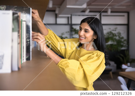 Young Indian woman browsing through books in bookstore 129212326