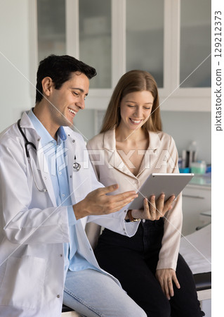 Positive physician doctor discussing scanning results on tablet with patient 129212373