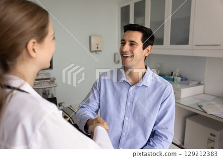Cheerful young Latin man thanking female physician 129212383