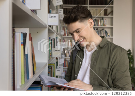 Happy male student flip through pages of paper book 129212385