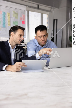 Teammates working on shared task using tablet and laptop Teammates working on shared task using tablet and laptop 129212538