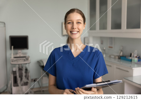 Positive ultrasound diagnosing doctor in blue scrubs posing in office 129212615