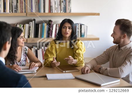 Four professionals engaged in discussion gathered in conference room Four professionals engaged in discussion gathered in conference room 129212669