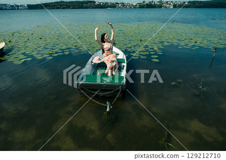 The girl sits comfortably in the boat on calm water 129212710