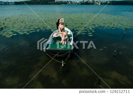 The girl sits comfortably in the boat on calm water 129212711