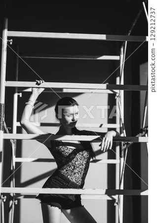 A girl wearing short shorts and a T-shirt is standing next to a frame scaffolding A girl wearing short shorts and a T-shirt is standing next to a frame scaffolding 129212737