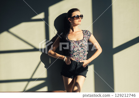 A girl in a fashionable outfit stands next to a metal structure 129212746