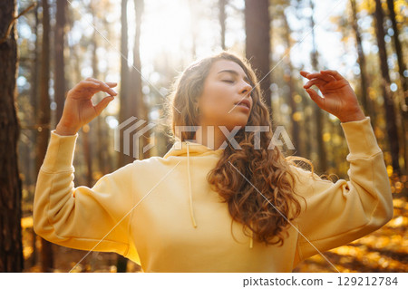Beautiful woman practices yoga in the autumn forest. Lifestyle and meditation concept. Beautiful woman practices yoga in the autumn forest. Lifestyle and meditation concept. 129212784