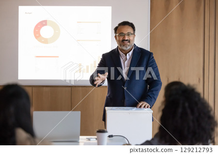Inspired smiling mature businessman speaking from lectern on boardroom meeting Inspired smiling mature businessman speaking from lectern on boardroom meeting 129212793