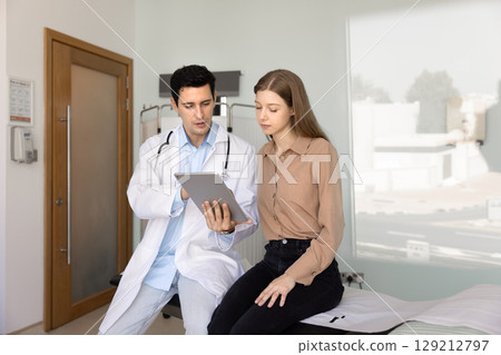 Serious young Hispanic physician man explaining medical report Serious young Hispanic physician man explaining medical report 129212797