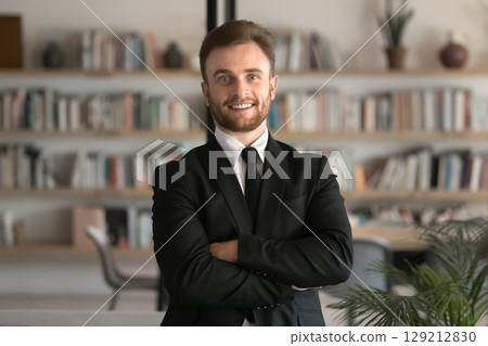 Confident young businessman dressed in formal attire posing in office Confident young businessman dressed in formal attire posing in office 129212830