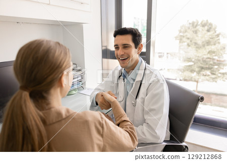 Happy young Hispanic doc giving greeting handshake 129212868