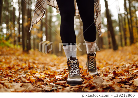 Woman's legs in boots in autumn foliage. Leaf fall. Lifestyle concept. 129212900