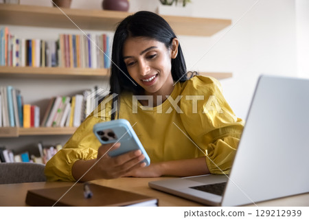 Young 25s Indian businesswoman using smartphone in workplace Young 25s Indian businesswoman using smartphone in workplace 129212939
