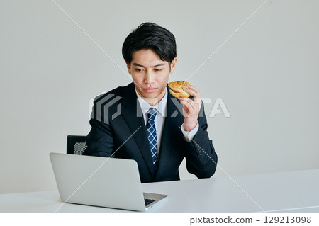 Young man eating a hamburger for lunch Young man eating a hamburger for lunch 129213098