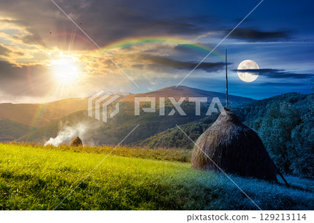 countryside landscape in mountains in summer. day and night time change concept. scenic view with trees and field in valley with sun and moon at twilight. rural scenery with haystack on grassy hill countryside landscape in mountains in summer. day and night time change concept. scenic view with trees and field in valley with sun and moon at twilight. rural scenery with haystack on grassy hill 129213114