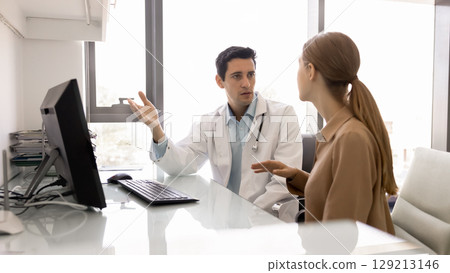 Serious male Latin physician explaining insurance terms to female patient Serious male Latin physician explaining insurance terms to female patient 129213146