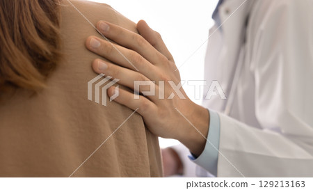 Male physician hand on shoulder of female patient 129213163