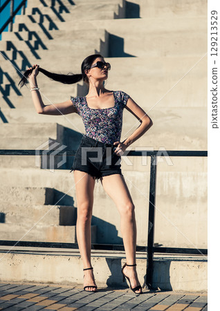 Near the wide steps, a charming girl with a long ponytail is sunbathing Near the wide steps, a charming girl with a long ponytail is sunbathing 129213529