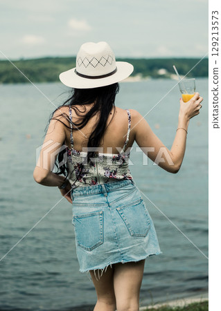 A young girl with a hat is sitting with her back turned A young girl with a hat is sitting with her back turned 129213573