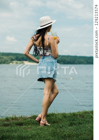 A young girl with a hat is sitting with her back turned 129213574