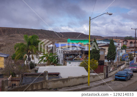 Colonia Libertad in Tijuana showcases a rugged neighborhood with colorful homes and palm trees, set against arid hills under a cloudy sky. Colonia Libertad in Tijuana showcases a rugged neighborhood with colorful homes and palm trees, set against arid hills under a cloudy sky. 129214033
