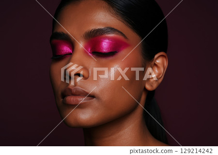 Confident woman with radiant skin and bold metallic magenta eye shadow, eyes closed, minimal makeup, dark studio background, AI Generative 129214242