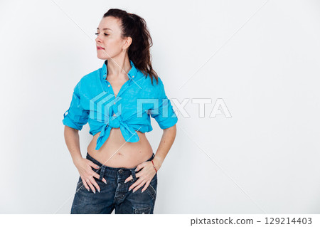 Beautiful brunette woman in jeans and blue shirt on white background 129214403