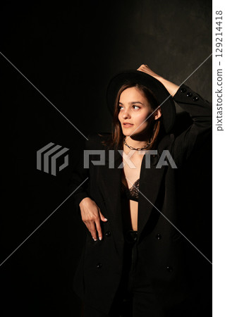 Woman in suit and hat in dark room 129214418
