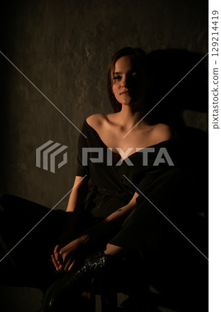 Fashionable woman in black suit in dark room 129214419