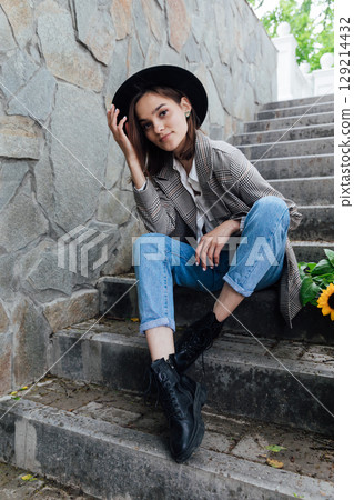 Beautiful fashion brunette woman wearing a hat with orange sunflowers Beautiful fashion brunette woman wearing a hat with orange sunflowers 129214432