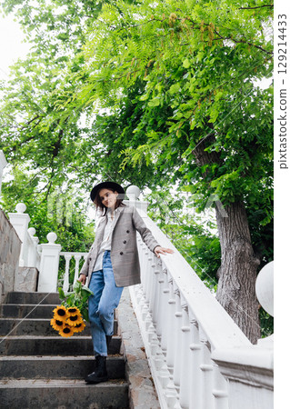 Beautiful fashion brunette woman wearing a hat with orange sunflowers 129214433