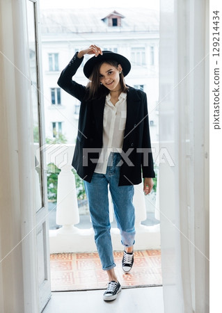 Beautiful fashionable brunette woman in jacket and hat posing in the background 129214434