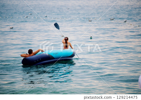 Unrecognizable girl and boy sailing on an inflatable boat. The girl is on oar Unrecognizable girl and boy sailing on an inflatable boat. The girl is on oar 129214475