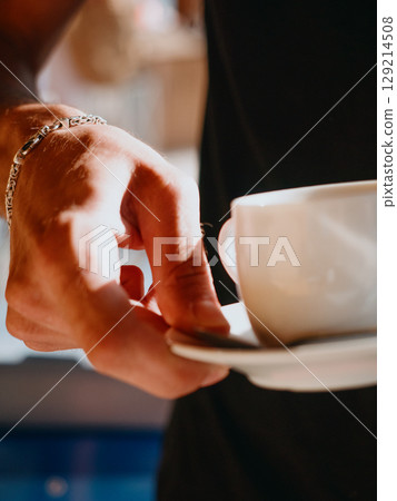 Waiter of summer beach cafe brings cup of coffee to customer. Summer relaxation 129214508