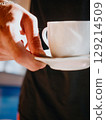 Waiter of summer beach cafe brings cup of coffee to customer. Summer relaxation 129214509