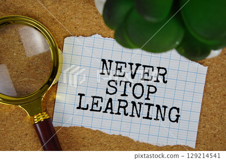 Never Stop Learning text written on paper with magnifying glass 129214541