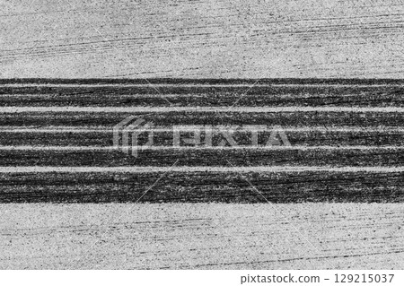 Black tire marks on road, Black rubber tire marks and tread marks, Tire trace track wheels texture and background, Auto tire tread grunge, Car wheel tyre tread track black tyre print, Aerial view. Black tire marks on road, Black rubber tire marks and tread marks, Tire trace track wheels texture and background, Auto tire tread grunge, Car wheel tyre tread track black tyre print, Aerial view. 129215037