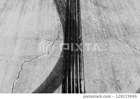 Black tire marks on road, Black rubber tire marks and tread marks, Tire trace track wheels texture and background, Auto tire tread grunge, Car wheel tyre tread track black tyre print, Aerial view. Black tire marks on road, Black rubber tire marks and tread marks, Tire trace track wheels texture and background, Auto tire tread grunge, Car wheel tyre tread track black tyre print, Aerial view. 129215049