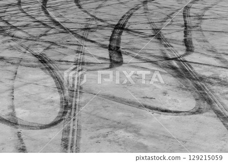 Black tire marks on road, Black rubber tire marks and tread marks, Tire trace track wheels texture and background, Auto tire tread grunge, Car wheel tyre tread track black tyre print, Aerial view. Black tire marks on road, Black rubber tire marks and tread marks, Tire trace track wheels texture and background, Auto tire tread grunge, Car wheel tyre tread track black tyre print, Aerial view. 129215059
