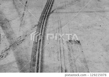 Black tire marks on road, Black rubber tire marks and tread marks, Tire trace track wheels texture and background, Auto tire tread grunge, Car wheel tyre tread track black tyre print, Aerial view. Black tire marks on road, Black rubber tire marks and tread marks, Tire trace track wheels texture and background, Auto tire tread grunge, Car wheel tyre tread track black tyre print, Aerial view. 129215078