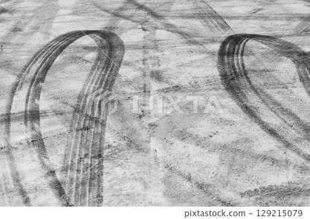 Black tire marks on road, Black rubber tire marks and tread marks, Tire trace track wheels texture and background, Auto tire tread grunge, Car wheel tyre tread track black tyre print, Aerial view. Black tire marks on road, Black rubber tire marks and tread marks, Tire trace track wheels texture and background, Auto tire tread grunge, Car wheel tyre tread track black tyre print, Aerial view. 129215079