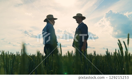 Farmers shaking hands in wheat field, Agriculture partnership on the field, Friendly handshake between farm workers, Rural businessmen agreement, Two men meeting on farm, Wheat field handshake at 129215253